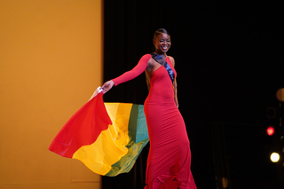 Proudly waving her Guinean flag, Nafissatou Camara, representing Guinea, dances to the music as she struts onto the stage for the first time this evening.