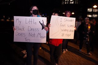 Two marchers carry signs with messages related to sexual violence as they marching through the campus Thursday night. 